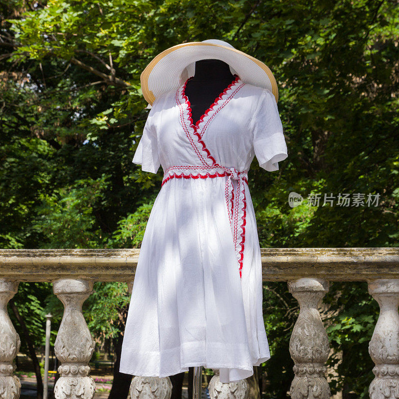 穿着白色衣服的人体模特。白色连衣裙，天然面料，红色元素。自定义裁剪。女士夏装配腰带