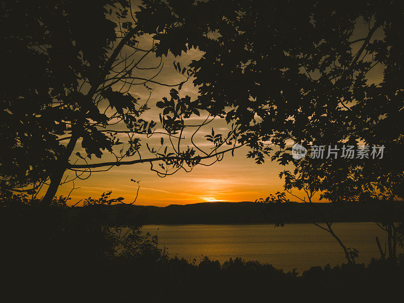 宁静的日落树的剪影在乔治湖，阿迪朗达克山，纽约