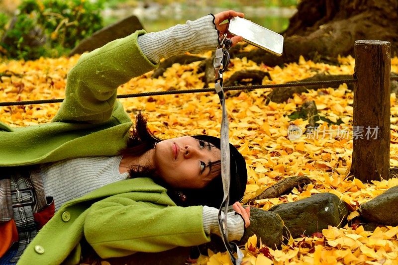 一名日本女子在秋天的银杏树下自拍