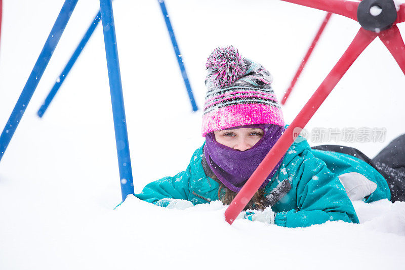 女孩在操场上的攀爬架下玩雪