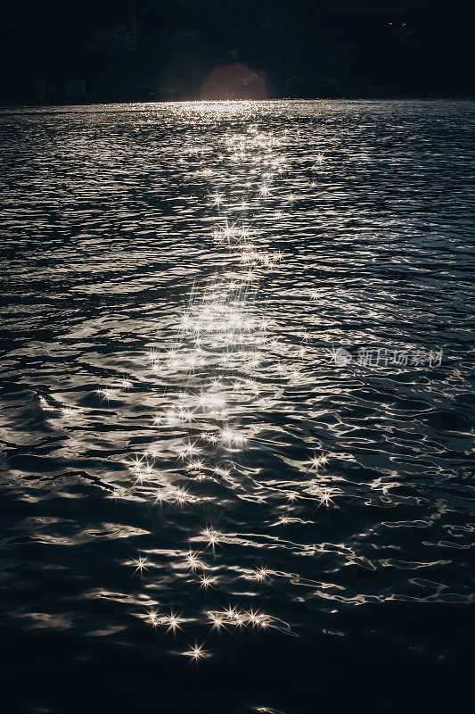 美丽的景色波光粼粼的水在马焦雷湖在阳光下的背景山，探索意大利。暑假去欧洲。阳光照在湖水上