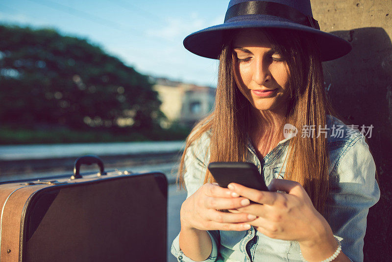 一名年轻女子在火车站等候时使用手机。