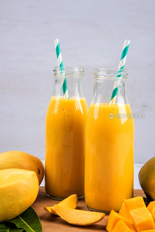 近距离的芒果冰沙在一个瓶子与芒果水果片和叶子