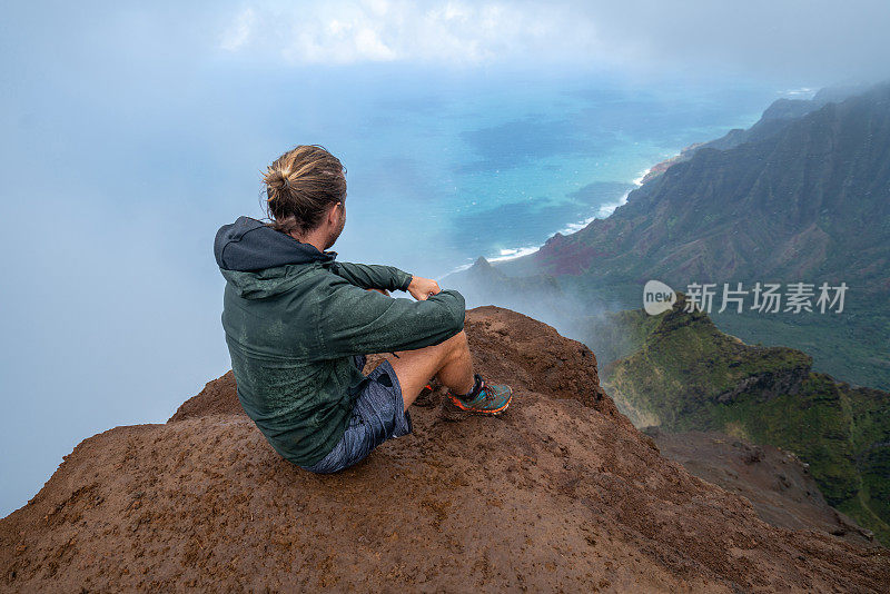 一名男子在夏威夷徒步旅行，从山顶眺望风景