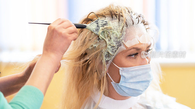 COVID-19期间，美发师在美容院用橡胶帽漂白金发