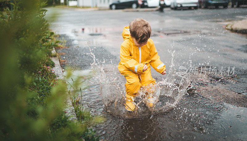 小男孩在雨中玩耍，跳进水里画画