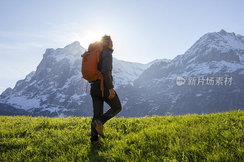 男性徒步者攀登山上的草甸斜坡