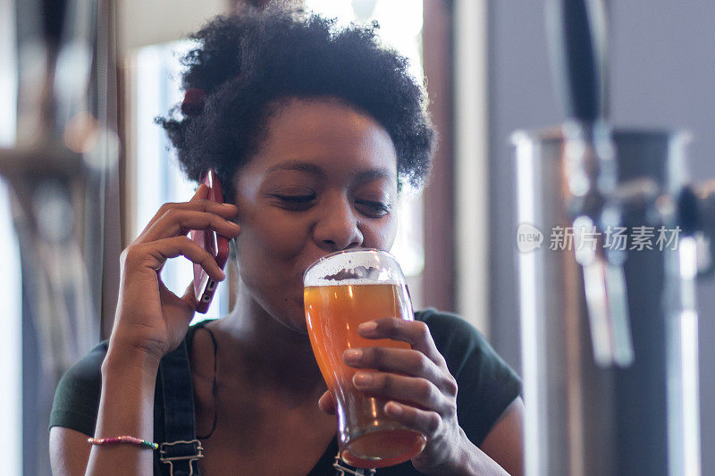肖像非洲妇女享受和喝啤酒在吧台