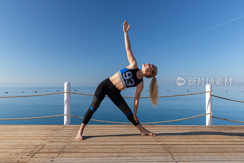 一个年轻女子在海边的木制码头上做瑜伽