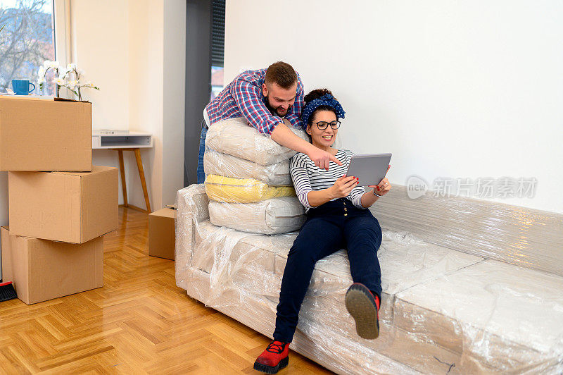 一对幸福的夫妇用平板电脑坐在沙发上