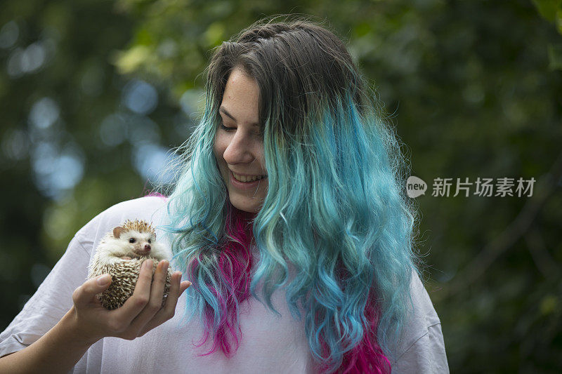 微笑的年轻成年妇女手持她的宠物刺猬在户外