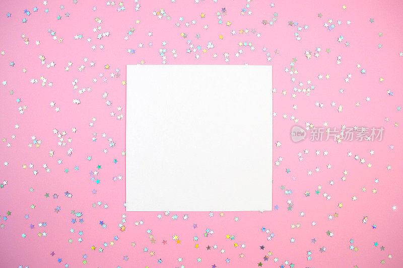 空白的白色方形纸卡和全息星星五彩纸屑平铺在粉红色的模型上
