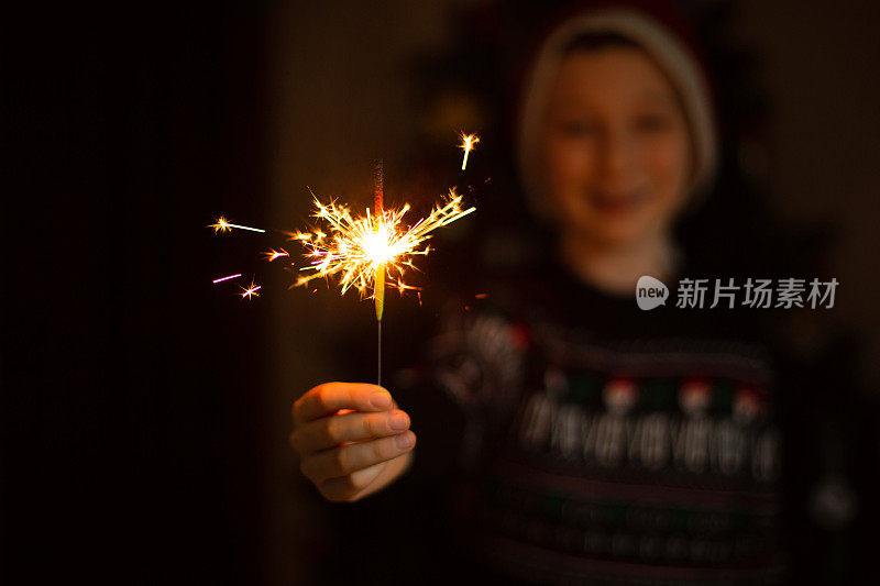 可爱的男孩点燃烟花庆祝新年。