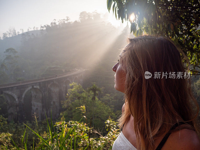 女游客在日落时凝视着著名的大桥