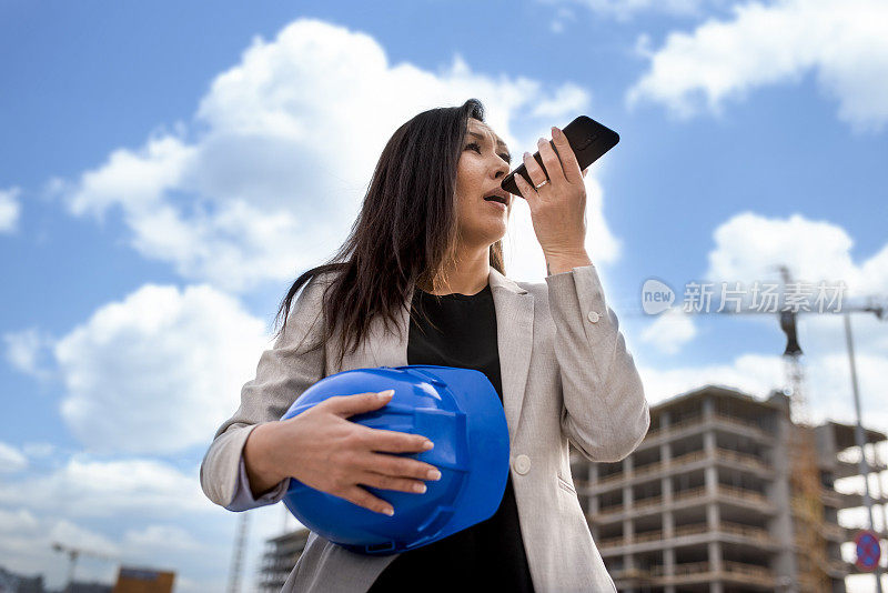 混血女商人在一个建筑工地作为建筑师使用手机库存照片