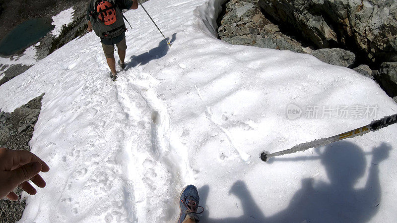 徒步旅行者沿着积雪的山坡跑下去