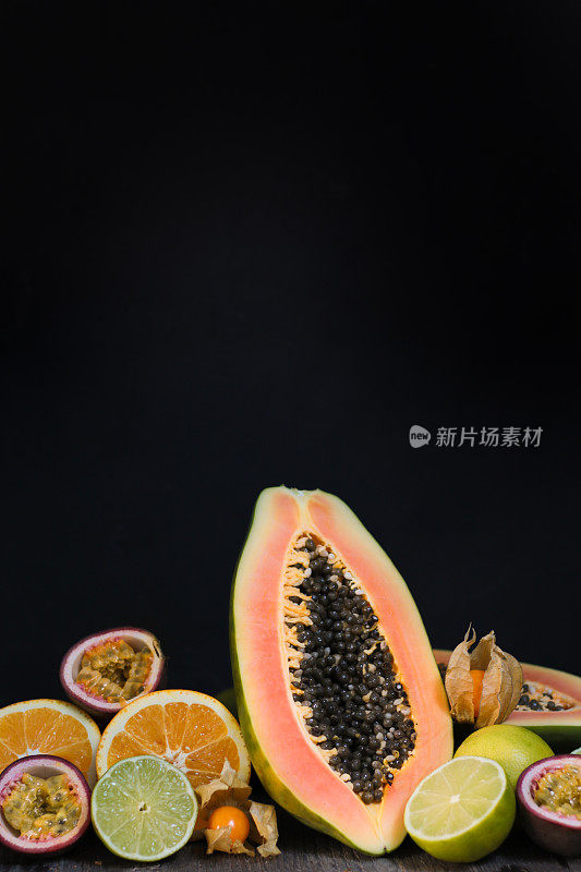 热带水果与木瓜和西番莲平躺在黑色的背景