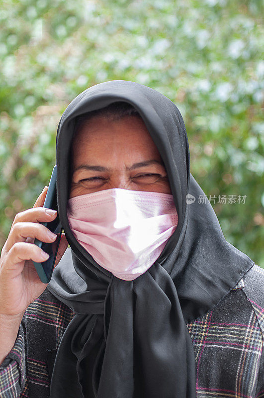 一名穆斯林妇女的肖像，用手机戴着防护面具