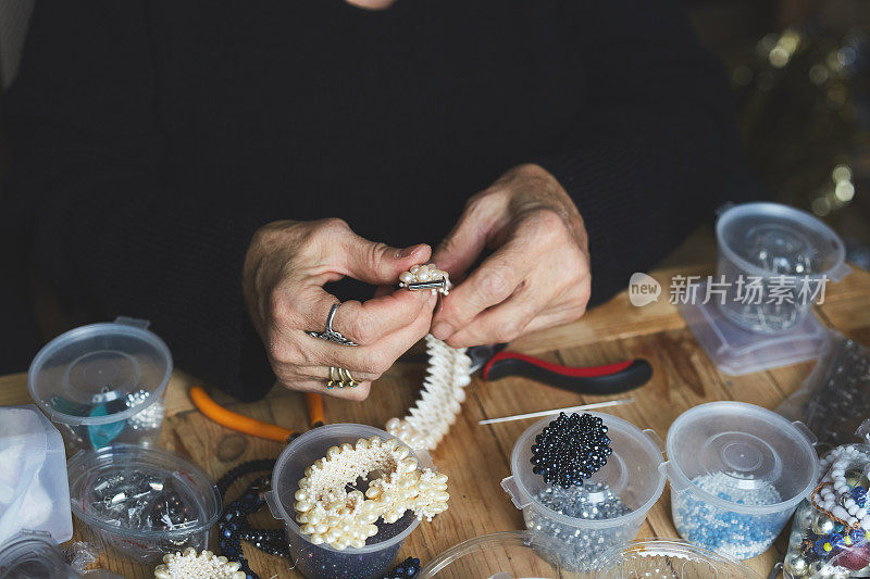 女人手工制作的手工首饰，饰品在木制背景上