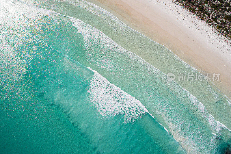 清澈的海浪拍打着白色的沙滩，绿松石色的海水