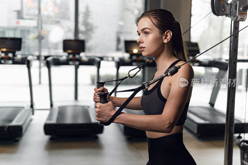 穿着运动服的女人在健身房用机器锻炼。