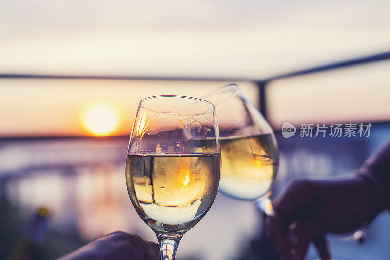 一对夫妇在日落时分用白葡萄酒敬酒。