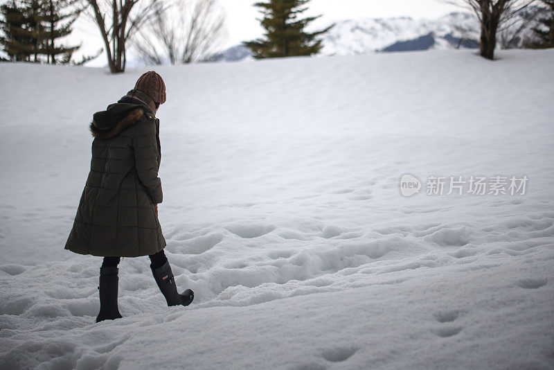 美丽的年轻女子走在堆积的雪地上