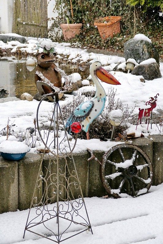 冬天回来了。2021年3月有暴风雪的花园和池塘。巴伐利亚,德国。