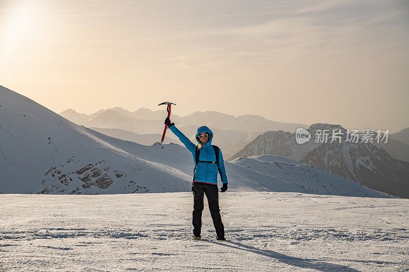 在一个美丽的冬日里，一位女性攀登者举着一把冰斧。
