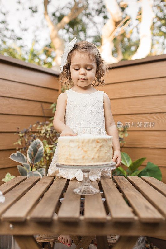 新冠肺炎期间，小女孩在家的2岁生日派对上吃着简单的白奶油生日蛋糕