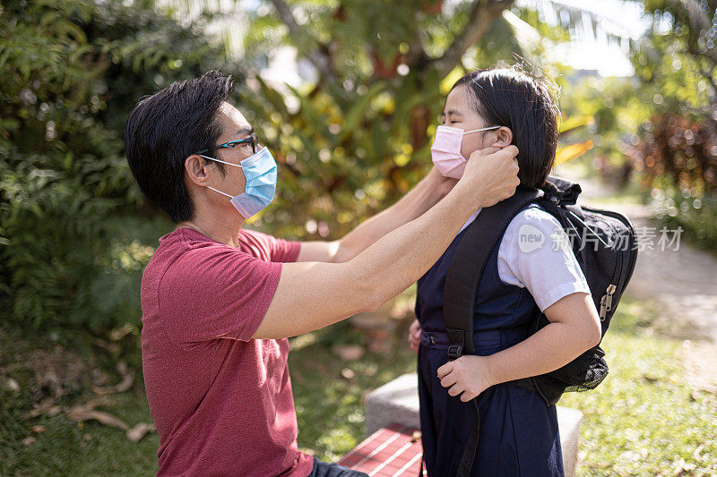 亚洲华人单身父亲帮助女儿戴口罩，以保护后院的流行病