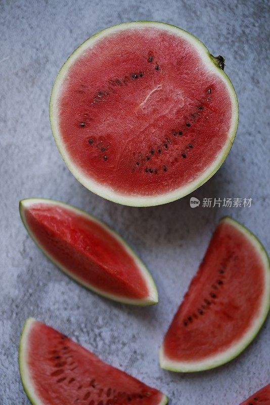 半片西瓜散落在灰色粗糙的水泥地面上，特写