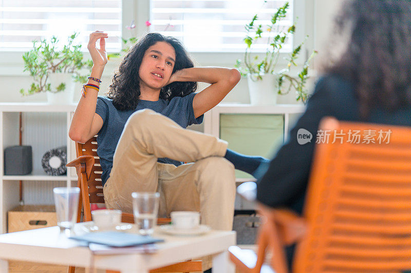 年轻的西班牙男性病人在她的办公室听女性心理治疗师