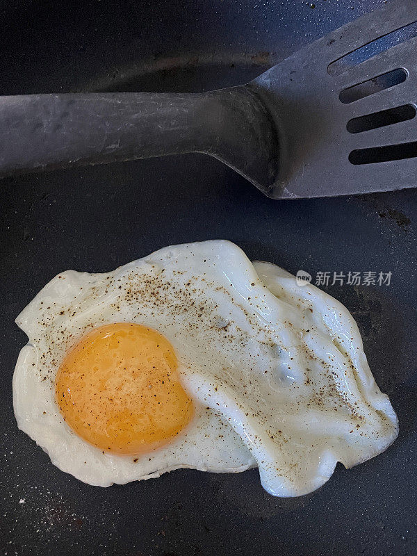 近距离拍摄的单面煎蛋，放在不粘锅里调味，用塑料铲，从高处俯瞰