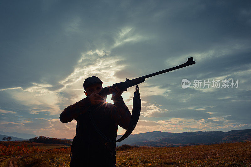 运动射击和狩猎——日落时分手持步枪的男子