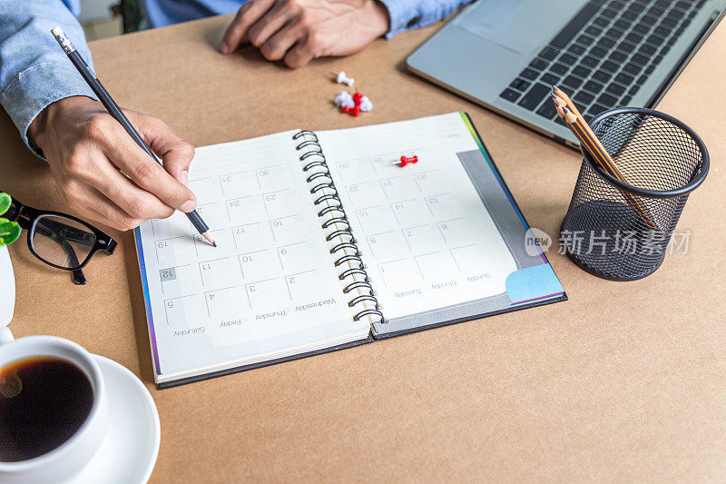 商人日程日历和提醒日程工作在线在家男人计划每日约会和假期旅行日记在他们的办公桌上。