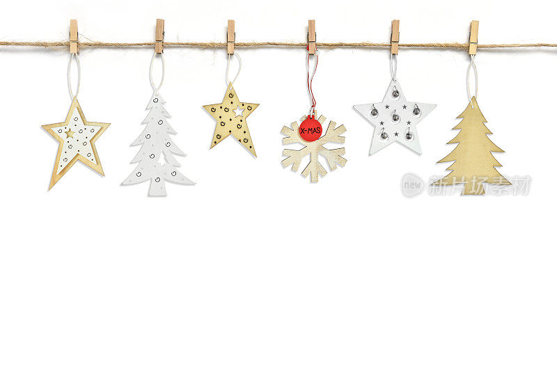 在白色背景上，各种各样的木头垂饰挂在晾衣夹上的绳子线上。冷杉树，雪花，圣诞节或新年的星星。