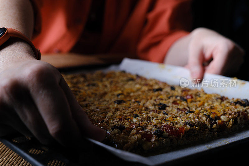 一个女人正在切割和包装自制的格兰诺拉燕麦卷