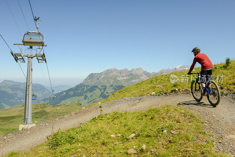 一名男子骑着山地车从瑞士阿尔卑斯山脉的约赫帕斯(Jochpass)穿过恩格尔堡(Engelberg)，沿着水流轨迹行驶