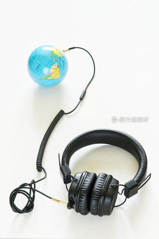 黑色有线耳机连接到一个小地球仪上。广播的概念，网络广播，播客和全球流行的音频hits