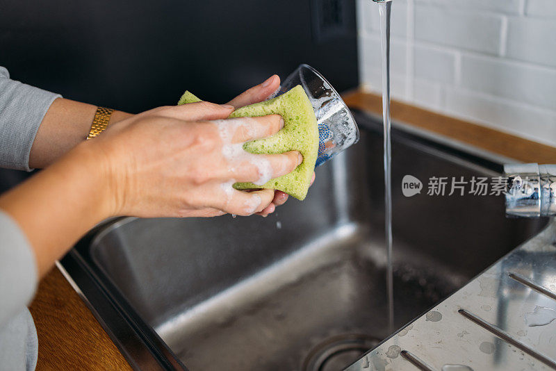 一个匿名女人的手在厨房水槽里洗眼镜