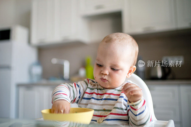 厨房里可爱的小男孩用手拿着碗吃东西