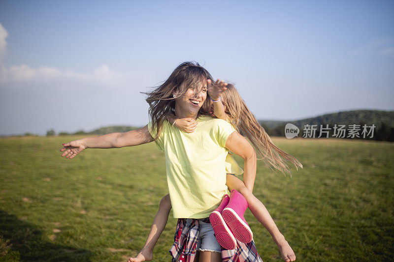 一个微笑的女人和她的女儿站在草地上纺纱。