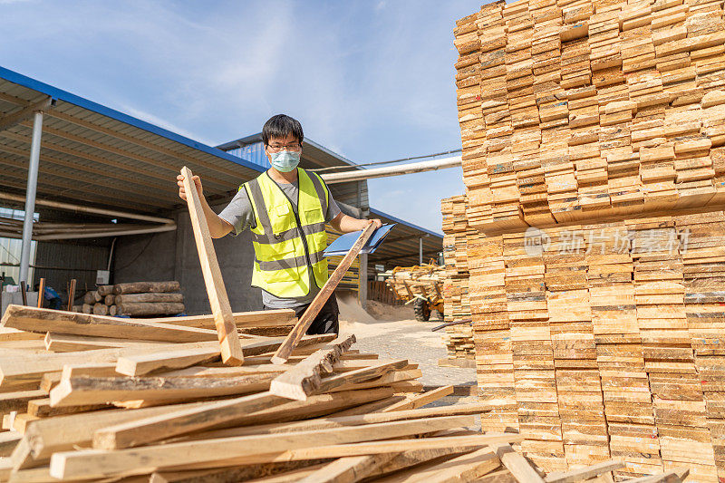 一名中年中国男性工人正在检查木板的质量