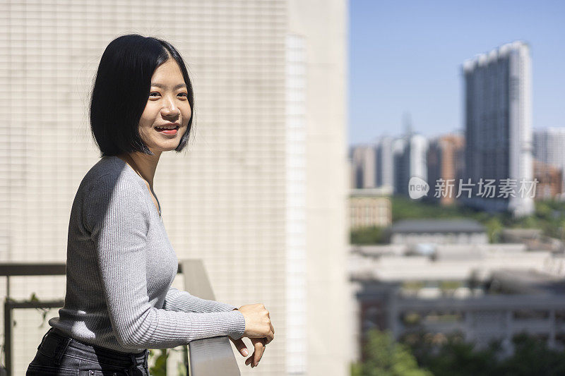 一位亚洲妇女在家里的阳台上望着远方