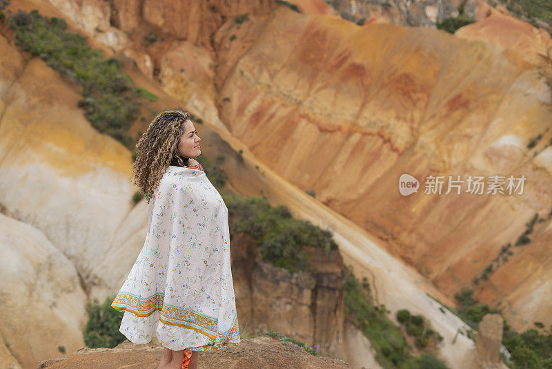 一位拉丁女子站在沙漠中的山上享受大自然