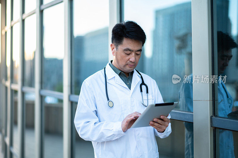 亚洲中年男医生在医院使用数字平板电脑