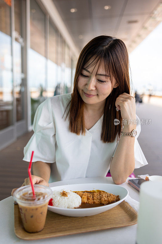 一位女士在户外咖啡馆吃咖喱午餐