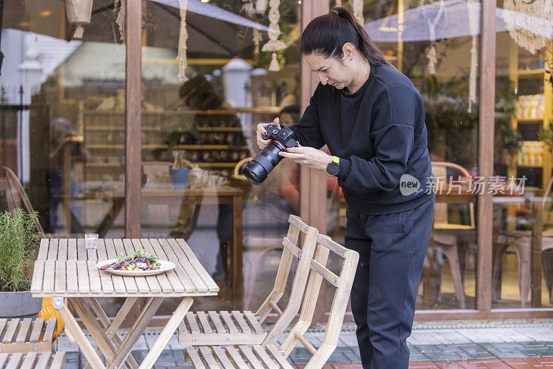 一位女摄影师正在用专业相机为社交媒体博客拍摄美食照片。