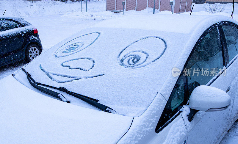 雪中汽车的挡风玻璃和画着微笑的眼睛。